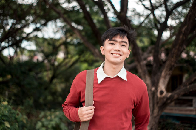 Male student standing outside red sweater